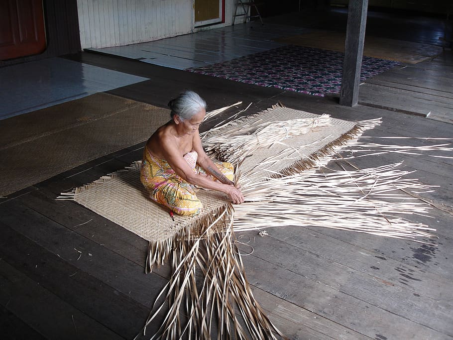 A Dayak woman weaves pandan in a traditional longhouse